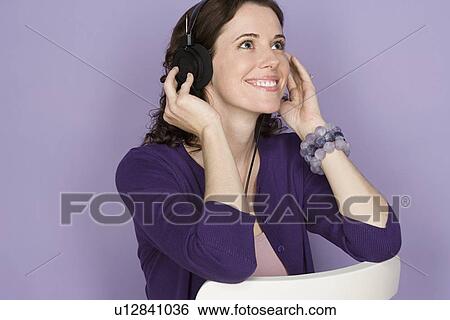 Portrait of smiling woman with headphones on purple background, studio shot View Large Photo Image Stock Photograph - Portrait of smiling woman with headphones on purple background, studio shot. Fotosearch