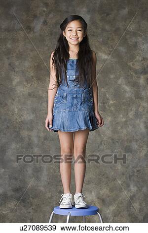 Stock Photo - Portrait of standing smiling girl (8-9), studio shot. Fotosearch
