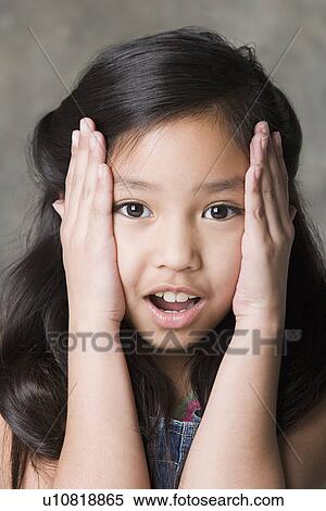 Stock Photography - Portrait of surprised girl (8-9), studio shot. Fotosearch