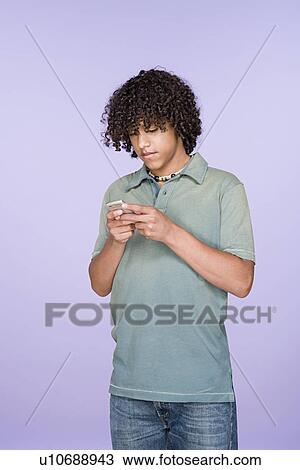 Stock Image - Portrait of teenage boy (14-15) texting on mobile phone. Fotosearch