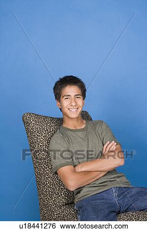 Stock Photograph - Portrait of teenage boy (16-17) sitting in chair. Fotosearch