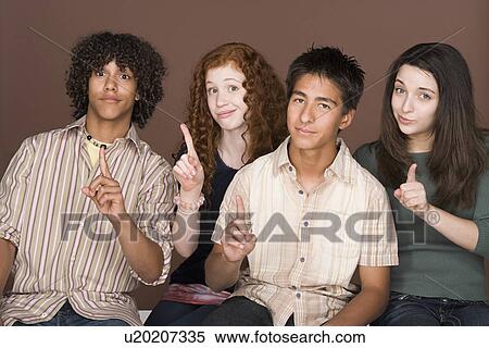Stock Photography - Portrait of teenagers (14-15, 16-17) with fingers up. Fotosearch