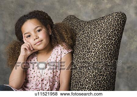 Stock Photo - Portrait of thoughtful girl (8-9) sitting, studio shot. Fotosearch