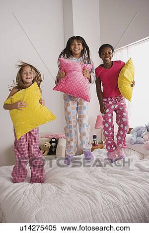 Portrait of three girls (10-11) jumping on bed at slumber party View Large Photo Image Stock Photography - Portrait of three girls (10-11) jumping on bed at slumber party. Fotosearch