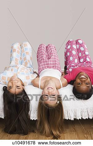 Portrait of three girls (10-11) lying on bed with heads down View Large Photo Image Stock Photo - Portrait of three girls (10-11) lying on bed with heads down . Fotosearch