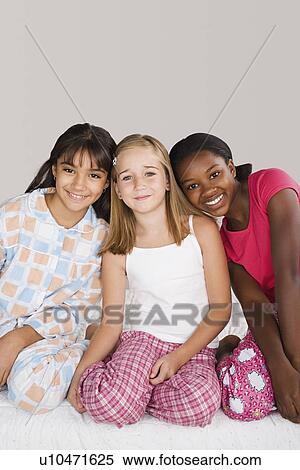 Portrait of three girls (10-11) sitting on bed at slumber party View Large Photo Image Stock Photography - Portrait of three girls (10-11) sitting on bed at slumber party. Fotosearch