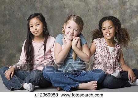 Portrait of three smiling girls (8-9) sitting together, studio shot View Large Photo Image Stock Photo - Portrait of three smiling girls (8-9) sitting together, studio shot. Fotosearch