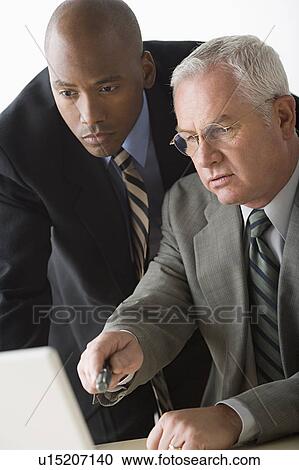 Stock Image - Portrait of two businessmen working on laptop. Fotosearch