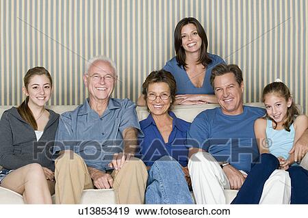 Portrait of two generation family with two girls (8-9, 14-15) sitting on sofa View Large Photo Image Stock Photo - Portrait of two generation family with two girls (8-9, 14-15) sitting on sofa. Fotosearch