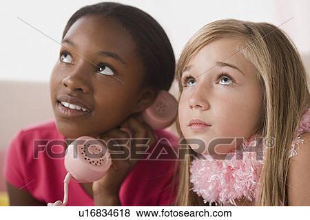 Stock Photo - Portrait of two girls (10-11) using phone at slumber party. Fotosearch