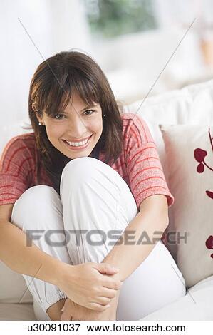 Stock Photo - Portrait of woman sitting on sofa. Fotosearch