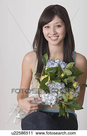 Stock Image - Portrait of young woman holding bunch of flowers. Fotosearch