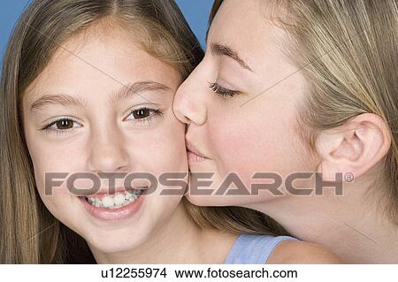 Portrait teenage girl (14-15) kissing younger sister View Large Photo Image Picture - Portrait teenage girl (14-15) kissing younger sister. Fotosearch