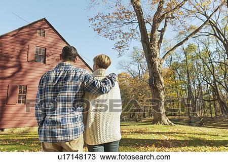 Stock Image - Rear view of couple facing cottage house. Fotosearch