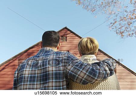 Stock Photography - Rear view of couple facing cottage house. Fotosearch
