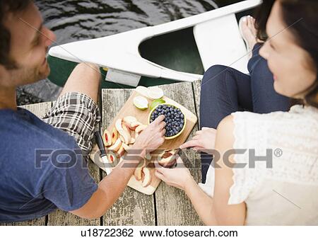 Stock Image - Roaring Brook Lake, Couple eating fruits on pier. Fotosearch