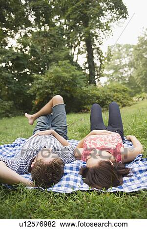 Stock Image - Roaring Brook Lake, Couple lying on grass. Fotosearch