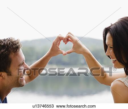 Stock Image - Roaring Brook Lake, Couple making heart shape with hands. Fotosearch