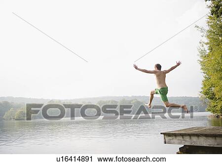 Stock Image - Roaring Brook Lake, Man jumping from pier to lake. Fotosearch
