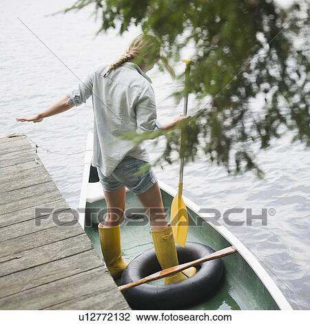 Stock Image - Roaring Brook Lake, Woman standing in boat with paddle. Fotosearch