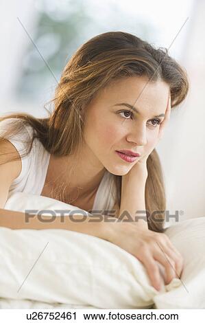 Stock Image - Sad woman lying on bed. Fotosearch