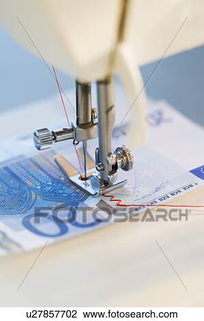 Stock Image - Sewing machine stitching 20 euro note, studio shot. Fotosearch