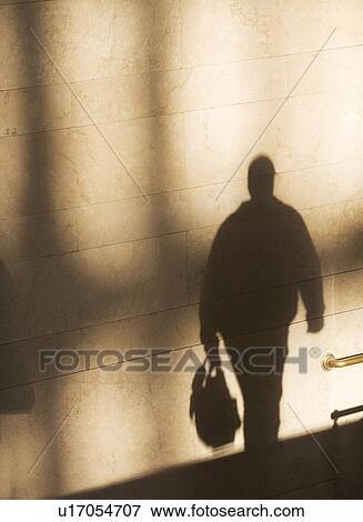 Stock Photo - Shadow of male pedestrian on sunlit wall. Fotosearch