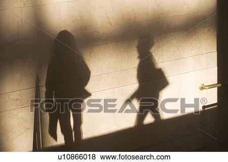 Stock Photo - Shadow of two female pedestrians on sunlit wall. Fotosearch