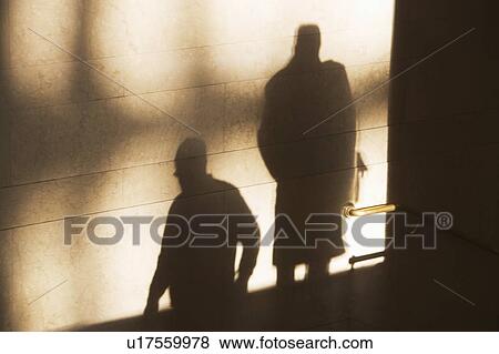 Shadow of two male pedestrians on sunlit wall View Large Photo Image Stock Photo - Shadow of two male pedestrians on sunlit wall. Fotosearch