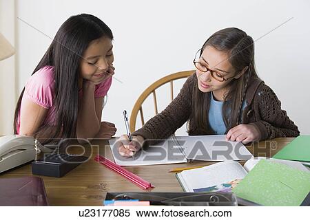 Stock Photography - Sisters (8-9, 10-11) doing homework. Fotosearch