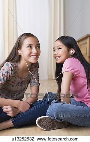 Sisters (8-9, 10-11) listening together music on headphones View Large Photo Image Stock Image - Sisters (8-9, 10-11) listening together music on headphones. Fotosearch