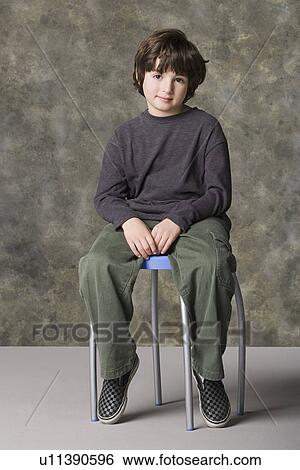 Smiling boy (6-7) sitting on chair, studio shot View Large Photo Image Stock Photograph - Smiling boy (6-7) sitting on chair, studio shot. Fotosearch