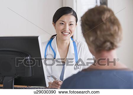 Smiling female doctor talking to patient in her office View Large Photo Image Stock Image - Smiling female doctor talking to patient in her office. Fotosearch