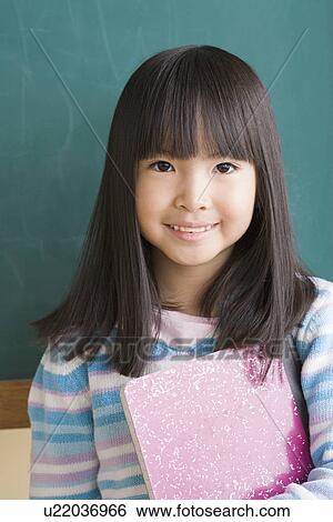 Smiling girl (6-7) against blackboard View Large Photo Image Stock Photograph - Smiling girl (6-7) against blackboard. Fotosearch