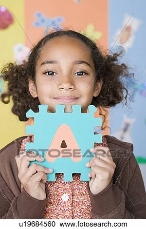 Smiling girl (6-7) holding letter A View Large Photo Image Stock Image - Smiling girl (6-7) holding letter A. Fotosearch