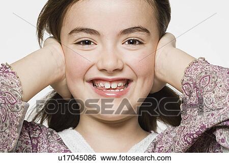 Stock Photograph - Smiling girl (8-9) covering her eyes, studio shot. Fotosearch