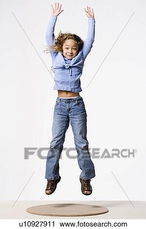 Stock Image - Smiling girl (8-9) jumping, studio shot. Fotosearch
