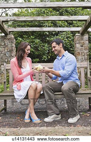 Smiling man giving gift to woman in garden View Large Photo Image Stock Image - Smiling man giving gift to woman in garden. Fotosearch