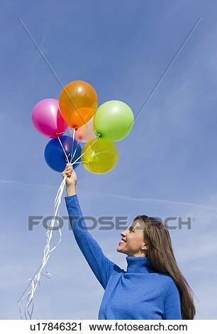 Smiling woman holding balloons View Large Photo Image Stock Image - Smiling woman holding balloons. Fotosearch