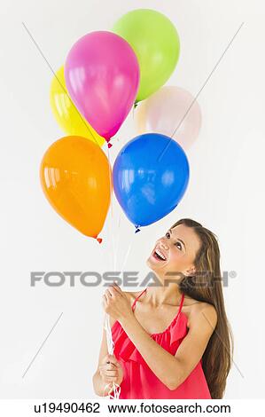 Smiling woman holding balloons, studio shot View Large Photo Image Stock Image - Smiling woman holding balloons, studio shot. Fotosearch