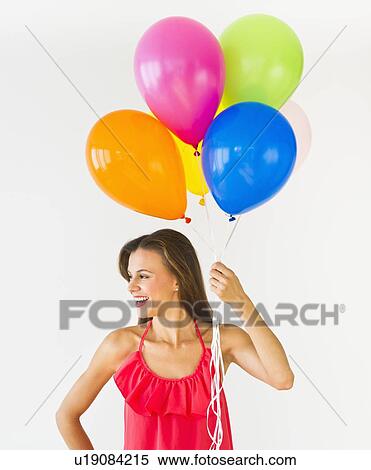 Stock Photography - Smiling woman holding balloons, studio shot. Fotosearch