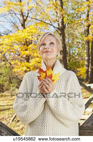 Smiling woman holding leaves in Autumn forest View Large Photo Image Stock Image - Smiling woman holding leaves in Autumn forest. Fotosearch