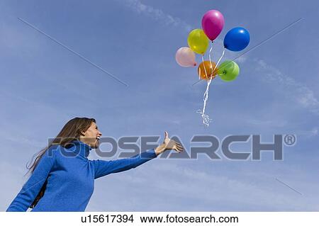 Smiling woman loosing balloons View Large Photo Image Picture - Smiling woman loosing balloons. Fotosearch