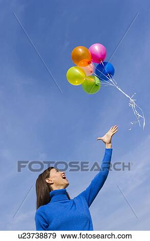 Smiling woman loosing balloons View Large Photo Image Stock Photo - Smiling woman loosing balloons. Fotosearch