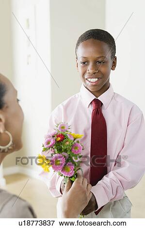 Son (12-13) giving flowers to Mother View Large Photo Image Stock Photo - Son (12-13) giving flowers to Mother. Fotosearch