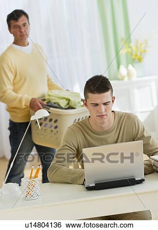Son (16-17) using laptop being observed by father View Large Photo Image Stock Photograph - Son (16-17) using laptop being observed by father. Fotosearch