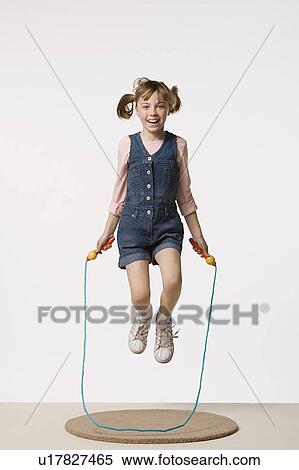 Stock Photography - Studio portrait of girl (8-9) jumping on rope. Fotosearch