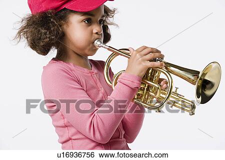 Stock Photograph - Studio portrait of girl (8-9) playing trumpet. Fotosearch