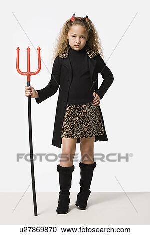 Stock Image - Studio portrait of girl (8-9) wearing Halloween costume with trident. Fotosearch