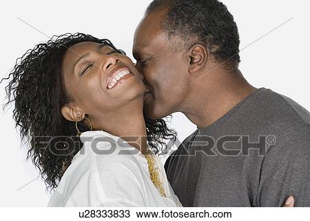 Stock Image - Studio portrait of mature couple kissing. Fotosearch